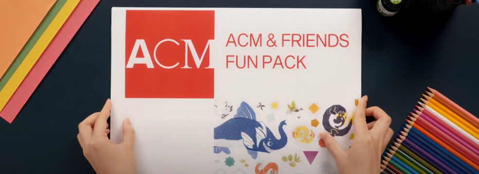 Two hands holding a printed copy of the ACM and Friends Fun Pack