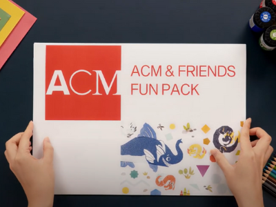 Two hands holding a printed copy of the ACM and Friends Fun Pack